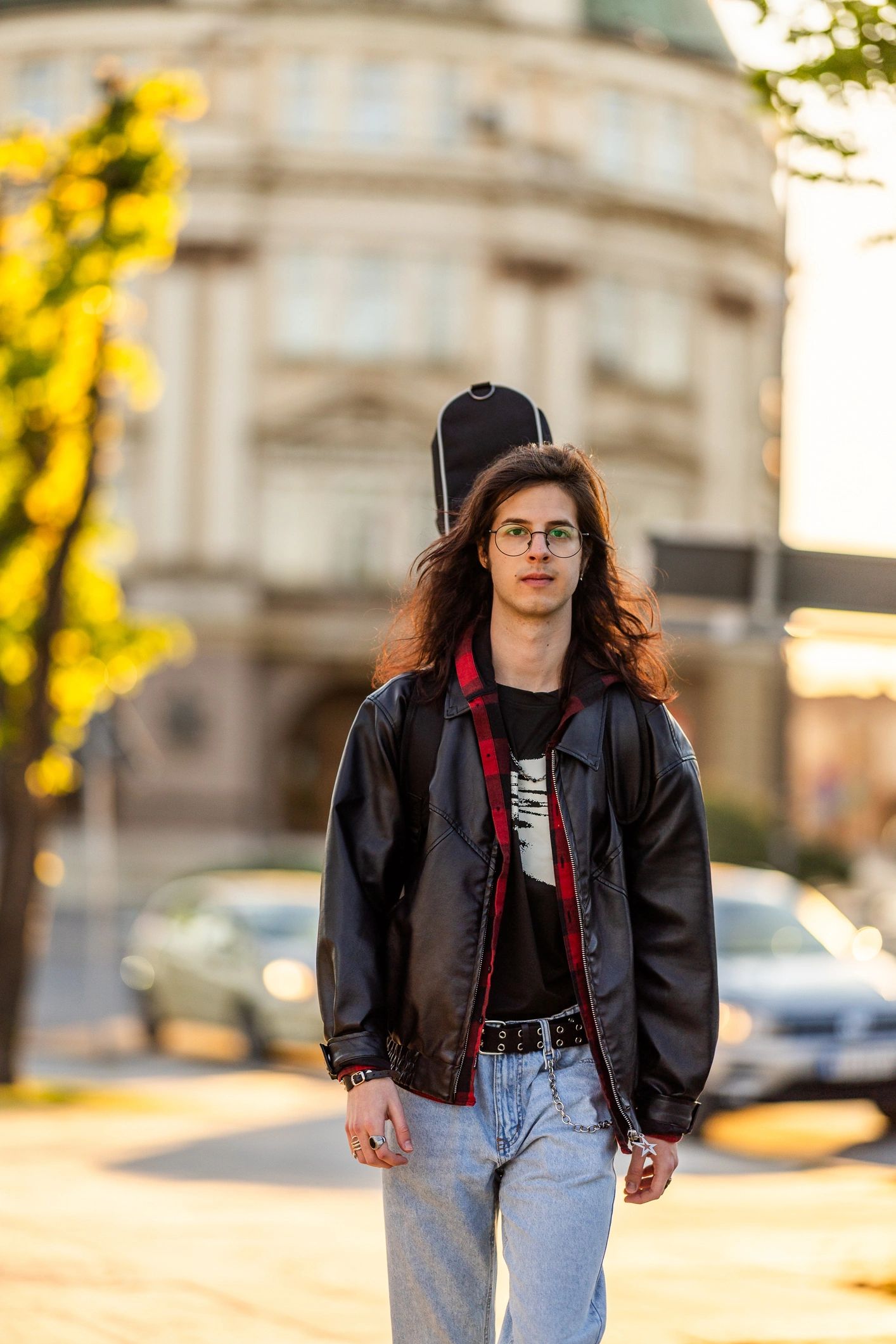 Musician carrying a guitar case at sunset
